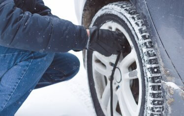 A man refills his tires air pressure in the snow