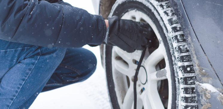 A man refills his tires air pressure in the snow