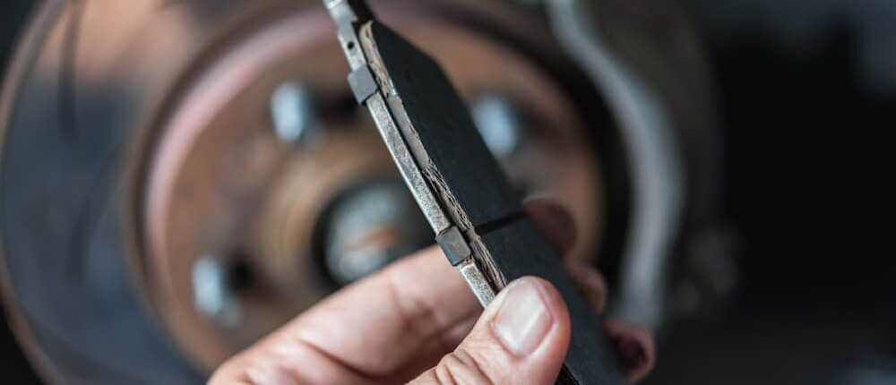 a hand holding a brake pad which is in the camera’s focus